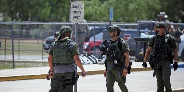 Law enforcement personnel stand outside Robb Elementary School following a shooting, Tuesday, May 24, 2022, in Uvalde, Texas.