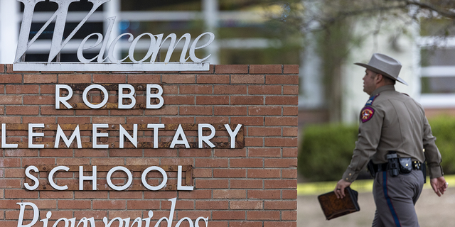 A state trooper walks past the Robb Elementary School sign in Uvalde, Texas, on Tuesday, May 24.