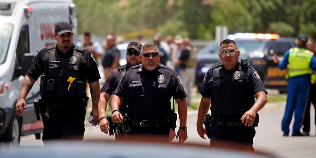 Police walk near Robb Elementary School following a shooting, Tuesday, May 24, 2022, in Uvalde, Texas.