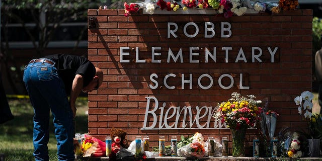 A law enforcement personnel lights a candle outside Robb Elementary School in Uvalde, Texas, Wednesday, May 25, 2022. 