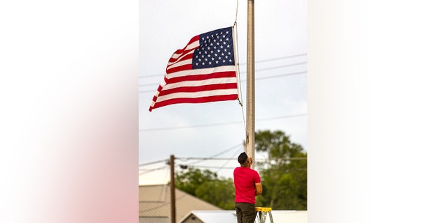 Janish Patel lowers the flag to half staff Tuesday, May 24, 2022, at his Uvalde, Texas, hotel hours after a gunman entered Robb Elementary School in Uvalde and killed multiple children and adults. (William Luther/The San Antonio Express-News via AP)