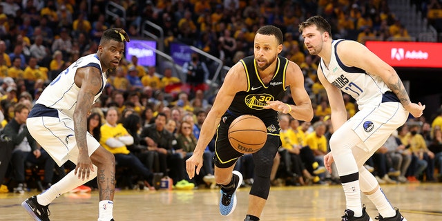 Stephen Curry of the Golden State Warriors drives past Reggie Bullock and Luka Doncic of the Dallas Mavericks on May 26, 2022, in San Francisco, California.