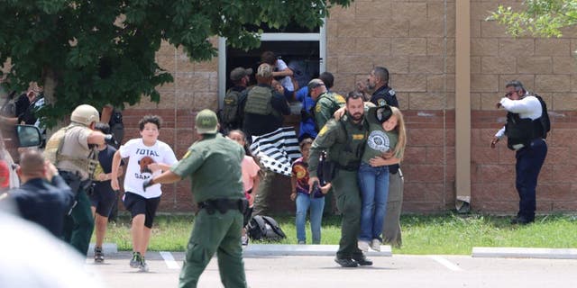 Children run to safety after escaping through a window during a mass shooting at Robb Elementary School.