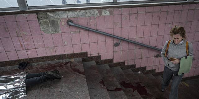 WARNING: GRAPHIC IMAGE: A woman walks next to the body of a man killed during shelling in Kharkiv, eastern Ukraine, Thursday, May 26.