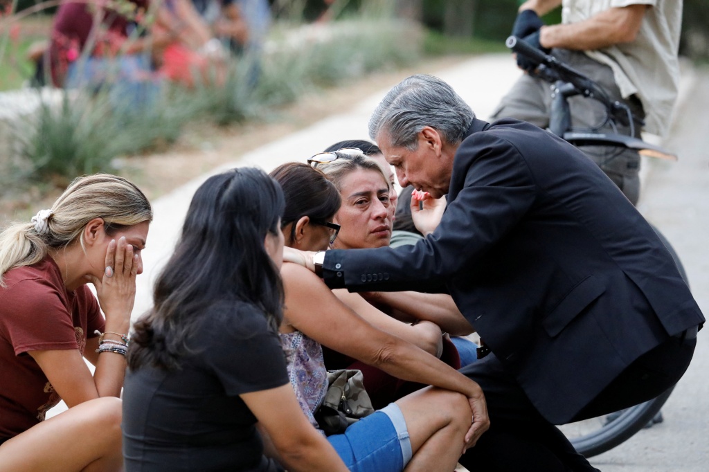 A priest comforts people outside Ssgt Willie de Leon Civic Center, where students were transported after the shooting in Uvalde on May 24, 2022. 