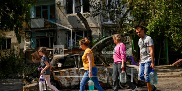 Residents carry water in front of an apartment building damaged in an overnight missile strike, in Sloviansk, Ukraine, Tuesday, May 31. 