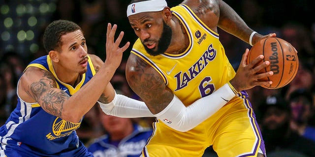 Los Angeles Lakers forward LeBron James, right, is defended by Golden State Warriors forward Juan Toscano-Anderson during the second half of a preseason game in Los Angeles Oct. 12, 2021.