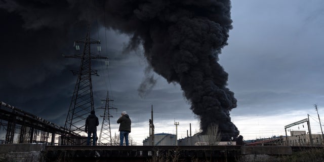 People watch as smoke rises in the air after shelling in Odesa, Ukraine, Sunday, April 3, 2022. 