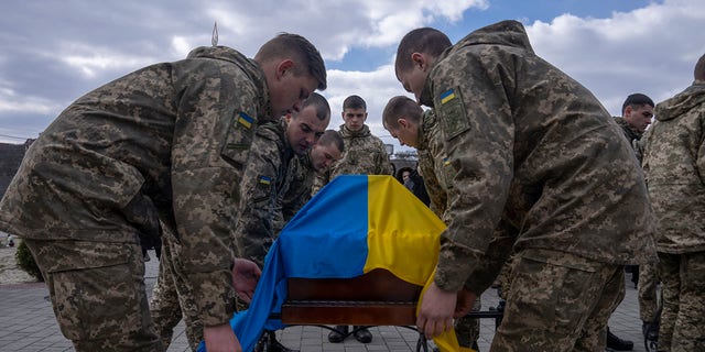 Soldiers place the Ukrainian flag on the coffin of 41-year-old soldier Simakov Oleksandr, during his funeral ceremony, after he was killed in action, at the Lychakiv cemetery, in Lviv, western Ukraine, Monday, April 4, 2022. 