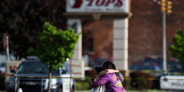 People hug outside the scene after a shooting at a supermarket on Saturday, May 14, 2022, in Buffalo, N.Y. 