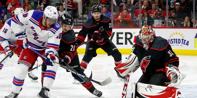 New York Rangers' Andrew Copp (18) battles for the puck with Carolina Hurricanes' Sebastian Aho (20) in front of Hurricanes goaltender Antti Raanta (32) with Hurricanes Brett Pesce (22) nearby during the first period of Game 7 of an NHL hockey Stanley Cup second-round playoff series in Raleigh, N.C., Monday, May 30, 2022.