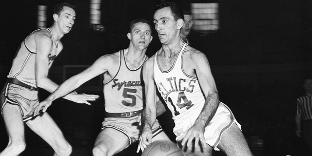 Bob Cousy (14) of the Boston Celtics moves into score through Syracuse Men, Red Rocha (left) and Paul Seymour (5), in the second quarter of the playoffs game at the Boston Arena.