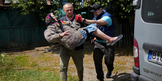 A woman is carried from her home in an evacuation by volunteers of the Vostok SOS charitable organization in Bakhmut, eastern Ukraine, on Friday, May 27.