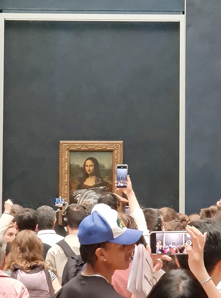 Visitors take pictures and video of the painting "Mona Lisa" after cake was smeared on the protective glass.