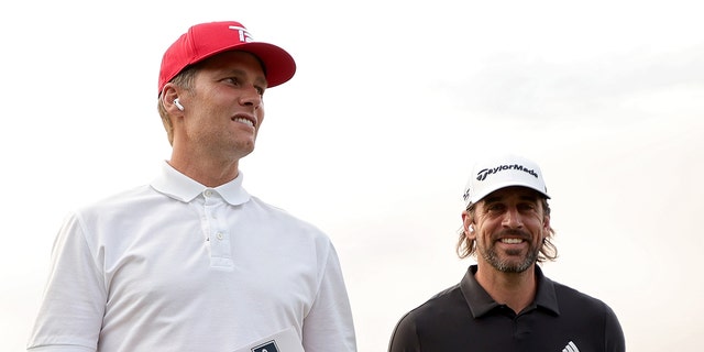 Tom Brady, left, and Aaron Rodgers walk across the course during Capital One's The Match at The Reserve at Moonlight Basin July 6, 2021, in Big Sky, Mont. 