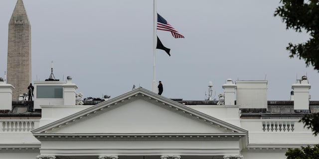 A U.S. Secret Service officer lowers the American flag to half-staff over the White House following the mass shooting at a Texas elementary school on May 24, 2022.