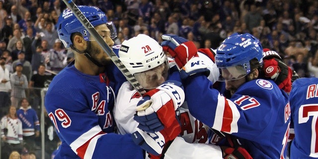 K'Andre Miller and Kevin Rooney of the Rangers hold off Ian Cole of the Carolina Hurricanes on May 24, 2022, in New York City.