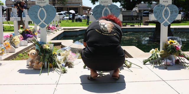 A mourner kneels at a memorial for one of the victims of Tuesday's mass shooting at an elementary school, in a park along Main Street on May 26, 2022, in Uvalde, Texas.