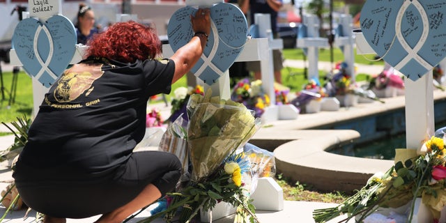 A mourner places her hand on a memorial for a victim of Tuesday's mass shooting at an elementary school in City of Uvalde Town Square May 26, 2022, in Uvalde, Texas. 