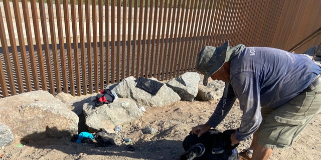 A volunteer cleans up the belongings left behind by undocumented people crossing through a gap in the border wall near Yuma, Arizona. (Ashley Soriano/Fox News)