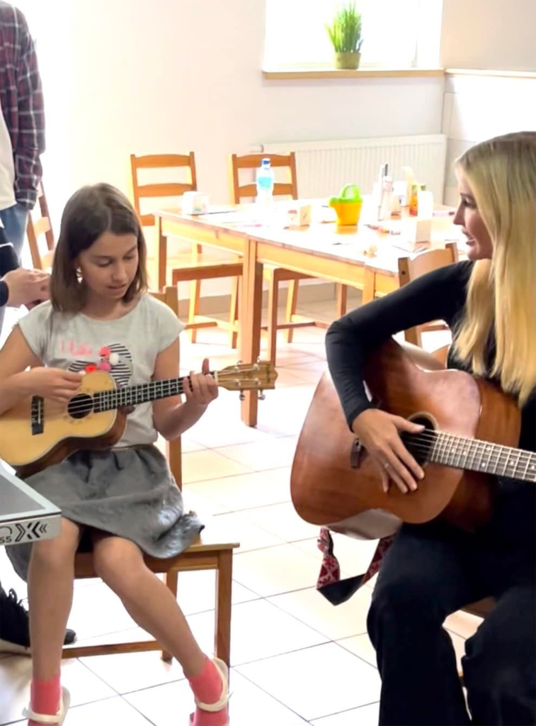 Ivanka Trump in Poland playing guitars with a young girl.