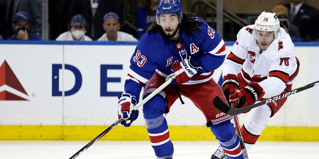 New York Rangers center Mika Zibanejad (93) passes in front of Carolina Hurricanes defenseman Brady Skjei in the first period of Game 3 of an NHL hockey Stanley Cup second-round playoff series, Sunday, May 22, 2022, in New York.