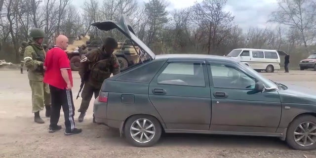 Russian forces search a vehicle at a checkpoint near Kharkiv, Ukraine.