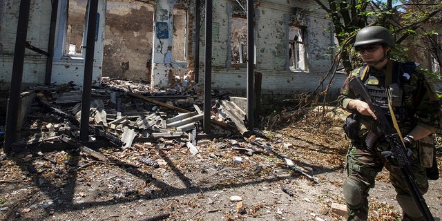 A police officer checks an area during an evacuation of local residents between shelling, amid Russia's attack on Ukraine, in the village of Novomykhailivka, in Donetsk region, Ukraine, May 29, 2022. 