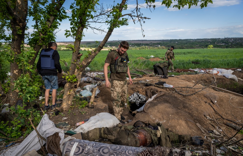 A Ukrainian serviceman checks the body of a dead Russian soldier in the village of Malaya Rohan, Ukraine, on May 16, 2022.