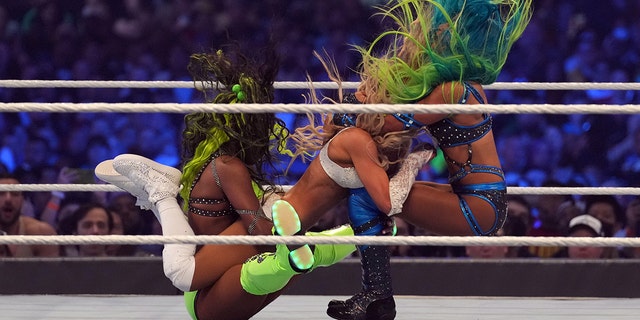 Apr 3, 2022; Arlington, TX, USA; Naomi (left) and Sasha Banks (right) attack Carmella during the women’s Tag Team Championship fatal four way match during WrestleMania at AT&amp;T Stadium.