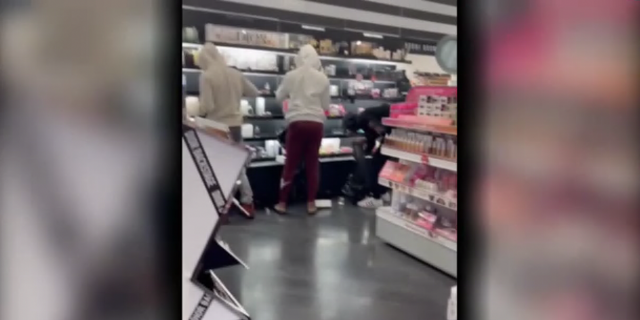 Thieves steal items off a shelves at Sephora beauty store in Los Angeles.