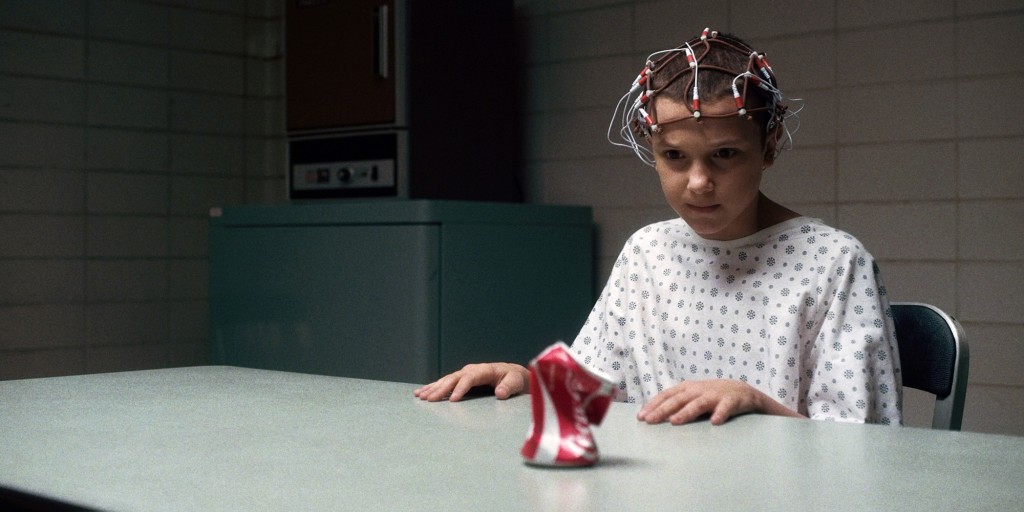 Millie Bobby Brown as Eleven focuses on crushing a Coca Cola can with her mind.