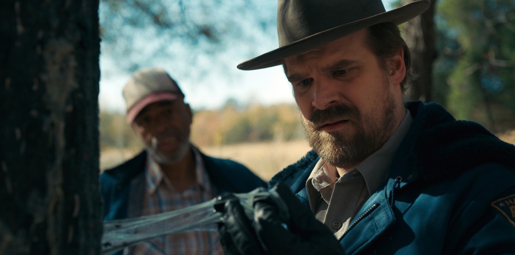 David Harbour as Chief Hopper holds evidence in his hands.