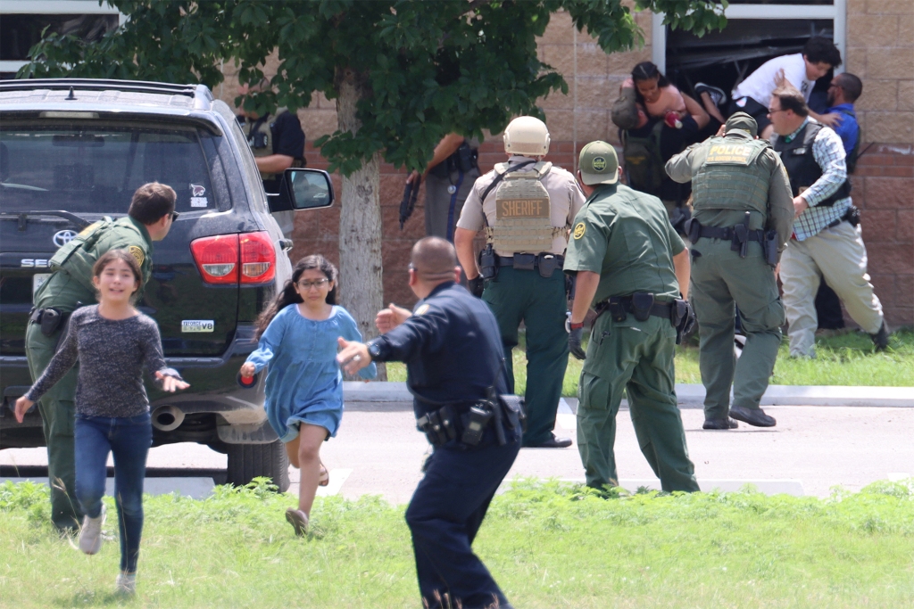 Law enforcement officers guide running children to safety during the mass shooting at Robb Elementary School.