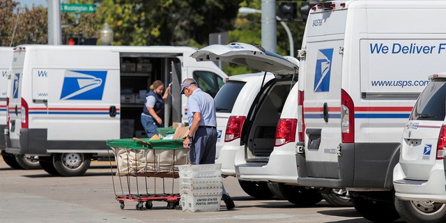 United States Postal Service (USPS) workers load mail into delivery trucks outside a post office in Royal Oak, Michigan, Aug. 22, 2020.