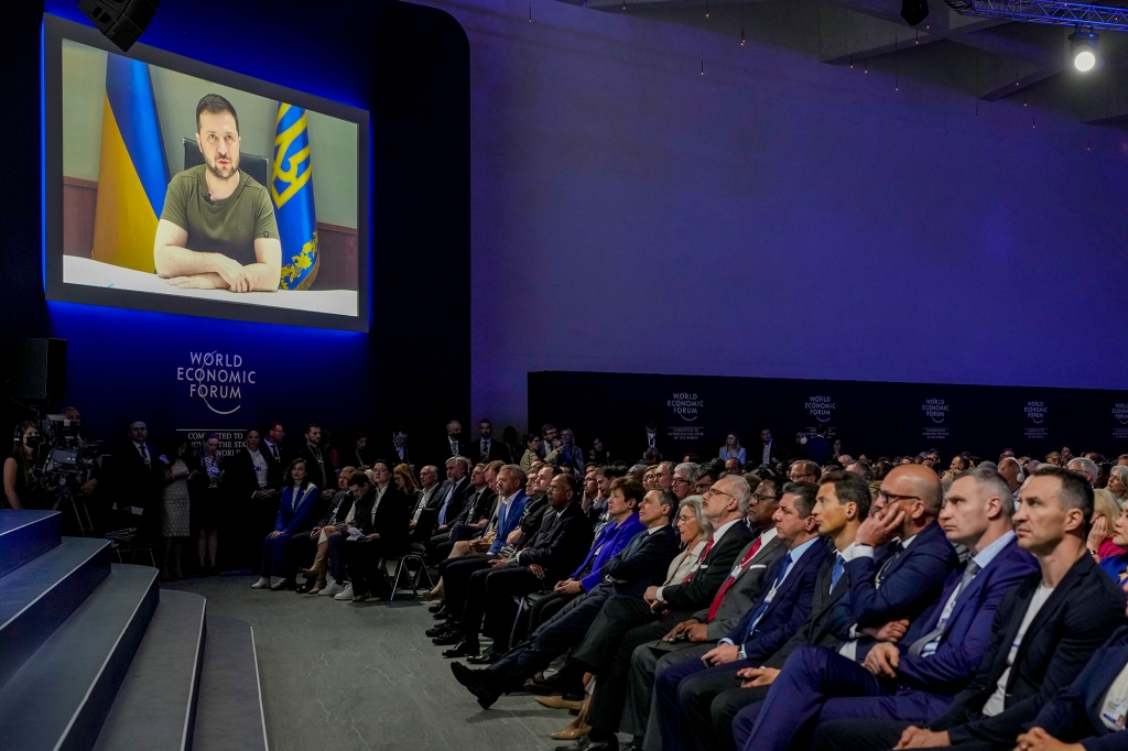 Ukrainian President Volodymyr Zelenskyy displayed on a screen as he addresses the audience from Kyiv on a screen during the World Economic Forum in Davos, Switzerland, Monday, May 23, 2022.