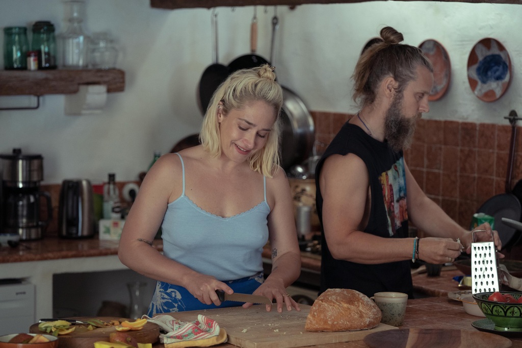 Jemima Kirke smiles and works in a kitchen. 