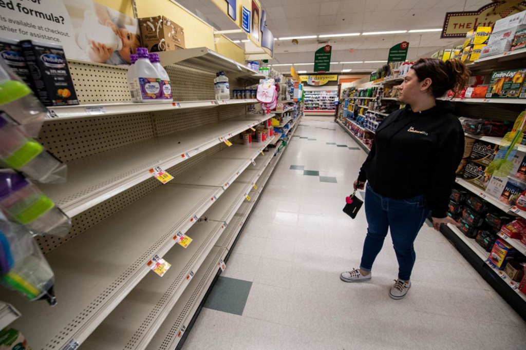 A woman gazes at empty shelves that inside a Masschusetts store on Wednesday. The shelves usually held baby formula, which has been cleared out amid a crippling shortage.