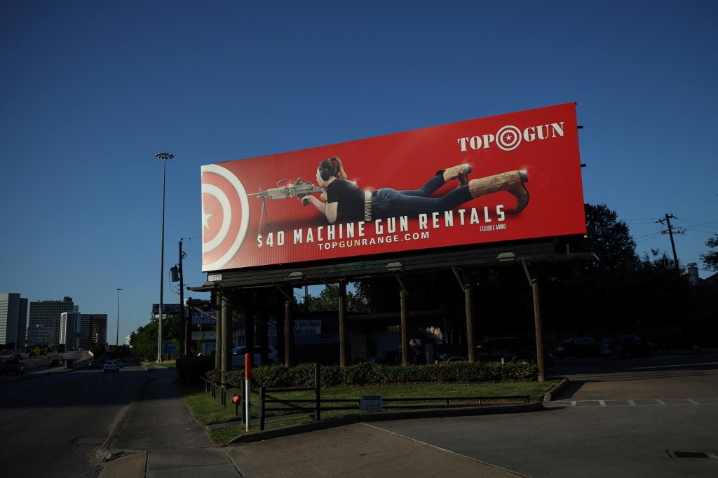 A billboard advertising machine gun rentals stands roadside near the site of the NRA annual convention.