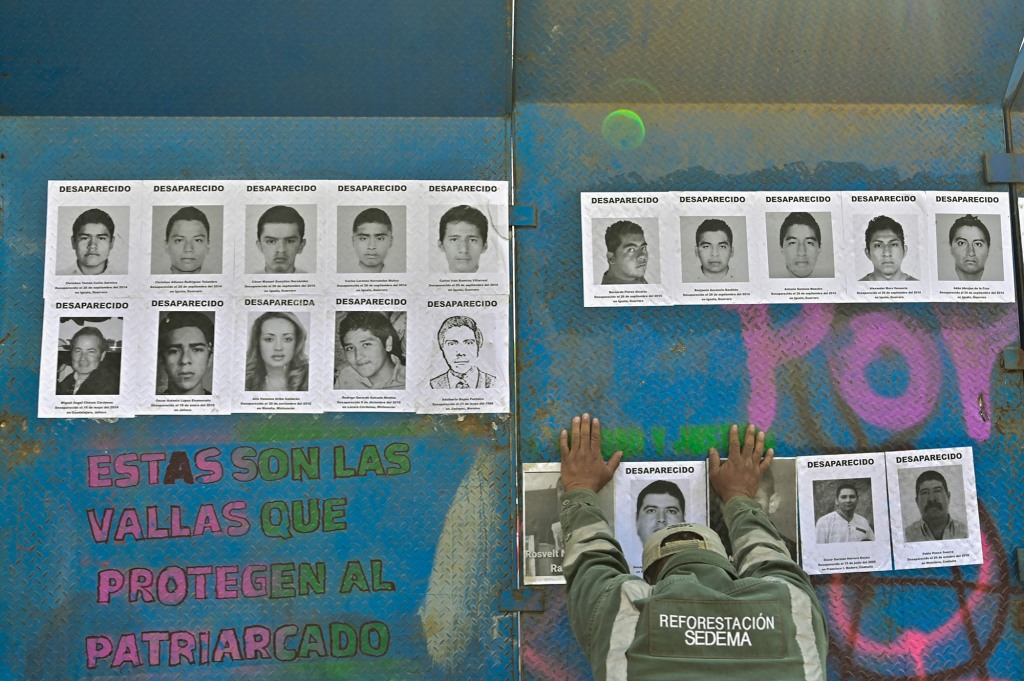 A worker of Mexico's City government moves a fence with photos of missing persons from the Glorieta de la Palma on Paseos de la Reforma Avenue, after relatives and members of search groups proposed to rename it 'Glorieta de Las y Los Desaparecidos' (Roundabout of the Disappeared), in Mexico City, on May 17, 2022