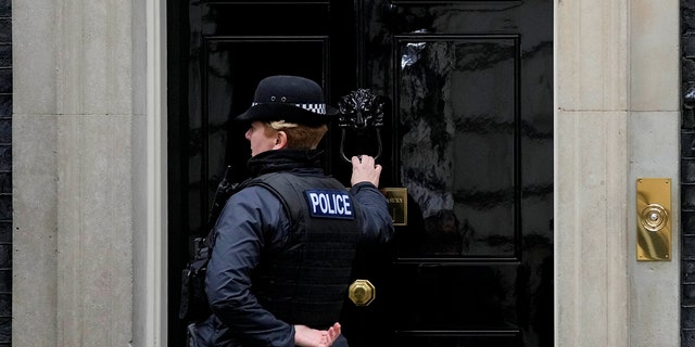 A police officer knocks on the dorr to 10 Downing Street in London, Tuesday, Jan. 11, 2022. Police are in contact with the Cabinet Office over claims the Prime Minister's aide organised a "bring your own booze" Downing Street drinks party in May 2020 during the first virus lockdown.