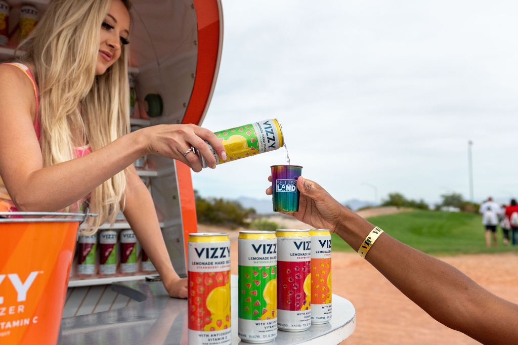 A woman pours a Vizzy hard seltzer drink into a cup.