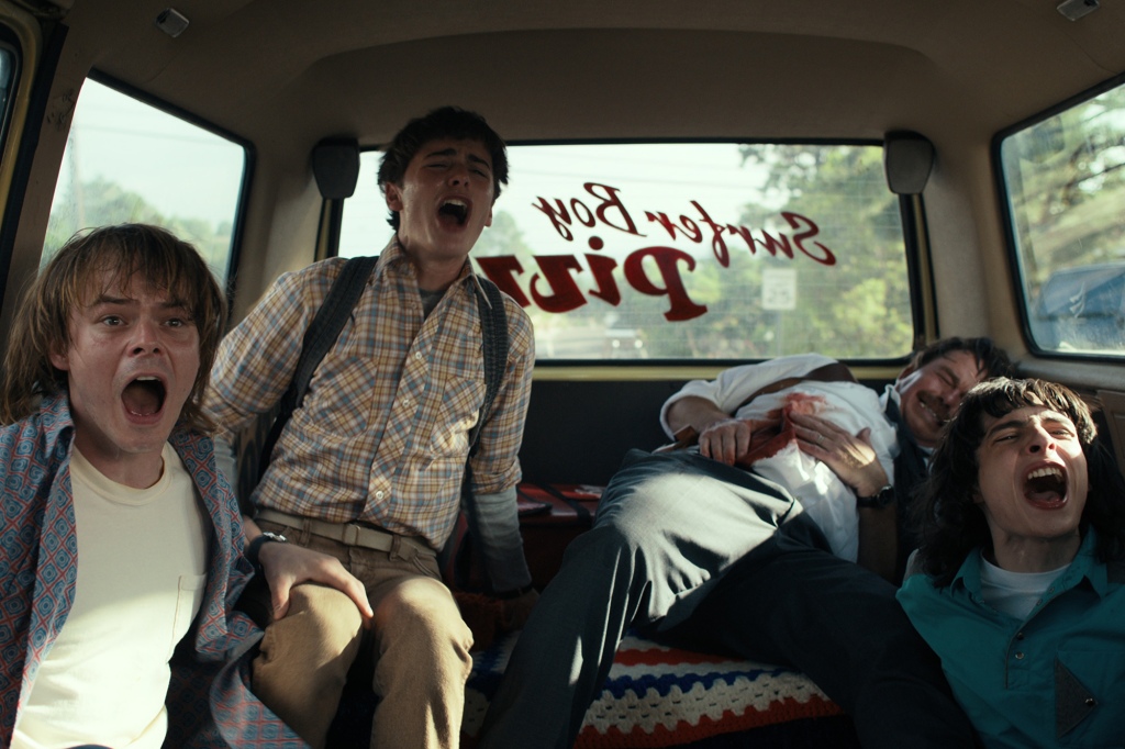 Jonathan Byers (Charlie Heaton), Will Byers (Noah Schnapp), and Mike Wheeler (Finn Wolfhard) shriek in the back of a van in "Stranger Things" Season 4. 