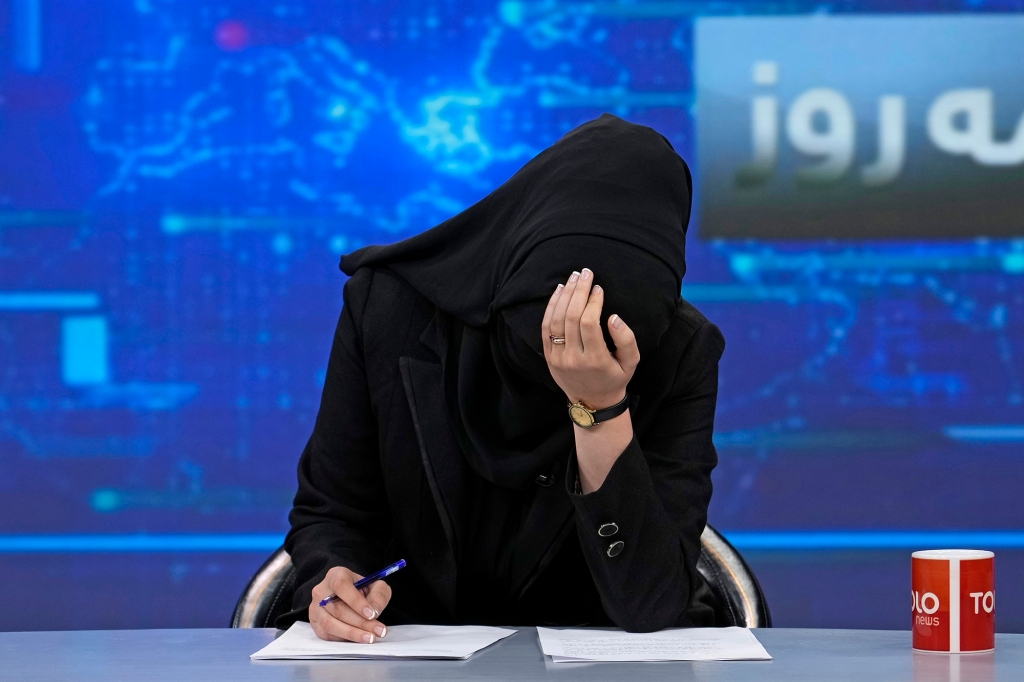 TV anchor Khatereh Ahmadi bows her head while wearing a face covering as she reads the news on TOLO NEWS, in Kabul, Afghanistan, Sunday, May 22, 2022. 