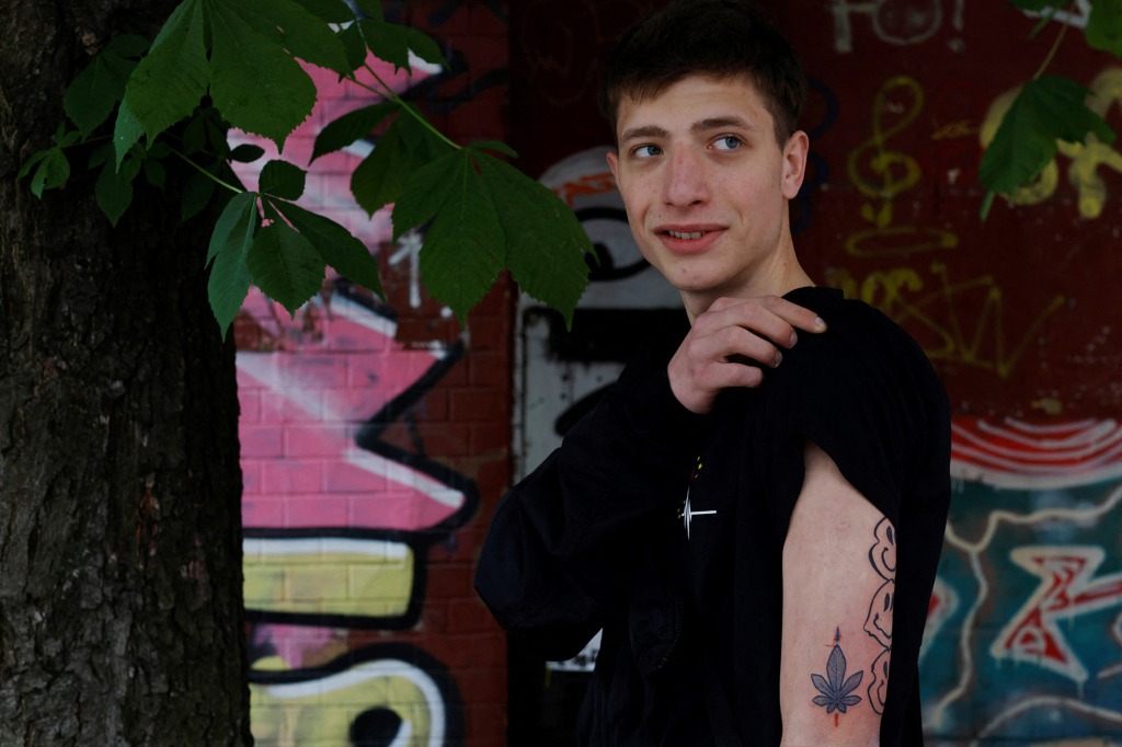 Zakhar Tokar, 19, poses with his chestnut leaf tattoo next to a chestnut tree at a weekly tattoo marathon held to raise funds for the military, amid Russia's invasion, in Podil, Kyiv, Ukraine May 21, 2022. 