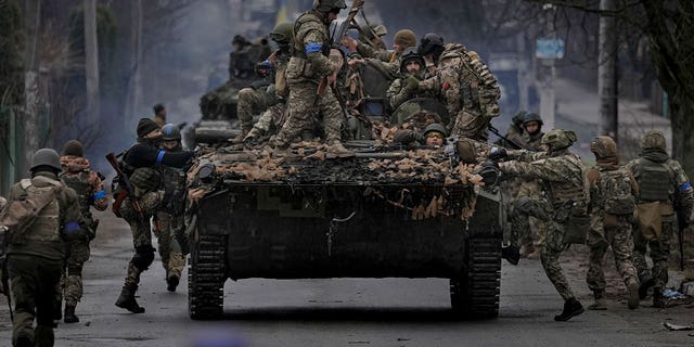 Ukrainian servicemen climb on a fighting vehicle outside Kyiv, Ukraine, Saturday, April 2, 2022. As Russian forces pull back from Ukraine's capital region, retreating troops are creating a "catastrophic" situation for civilians by leaving mines around homes, abandoned equipment and "even the bodies of those killed," President Volodymyr Zelenskyy warned Saturday. 