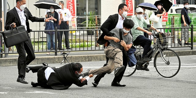 A man believed to have shot former Japanese Prime Minister Shinzo Abe is tackled by police officers in Nara, western Japan, on July 8.