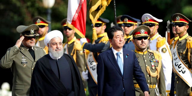 Japanese Prime Minister Shinzo Abe, center, reviews an honor guard as he is welcomed by Iranian President Hassan Rouhani, left, in an official arrival ceremony at the Saadabad Palace in Tehran, Iran, Wednesday, June 12, 2019. The Japanese leader is in Tehran on an mission to calm tensions between the U.S. and Iran. 