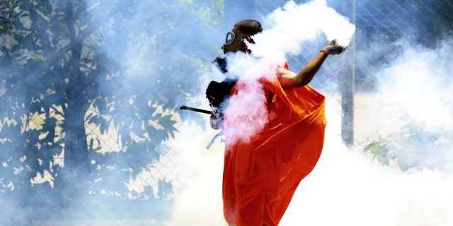 A man throws back a tear gas shell after it was fired by police to disperse the protesters in Colombo, Sri Lanka, Saturday, July 9, 2022. Sri Lankan protesters demanding that President Gotabaya Rajapaksa resign forced their way into his official residence on Saturday, a local television report said, as thousands of people took to the streets in the capital decrying the island nation's worst economic crisis in recent memory. (AP Photo/Amitha Thennakoon)