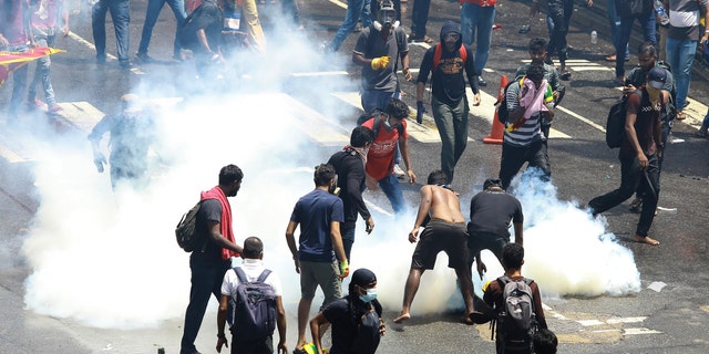 Protesters try to remove a tear gas shell after it was fired by police to disperse them in Colombo, Sri Lanka, Saturday, July 9, 2022. Sri Lankan protesters demanding that President Gotabaya Rajapaksa resign forced their way into his official residence on Saturday, a local television report said, as thousands of people took to the streets in the capital decrying the island nation's worst economic crisis in recent memory. (AP Photo/Amitha Thennakoon)